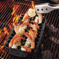 shrimp being cooked on the grill with tongs