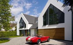 a red sports car is parked in front of a white house with two story windows