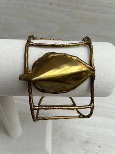 Vintage brass cage cuff bracelet from the 1970's. The center piece of the bracelet has a geometric leaf design that is reflective, very unique piece. This is an authentic vintage bracelet, no major flaws to note. These have been left natural and not polished.  Please feel free to message us if you have any questions.