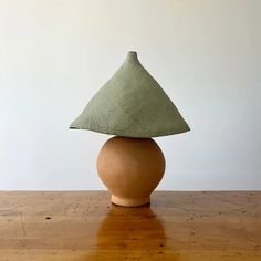 a wooden table topped with a brown vase and a green hat on top of it