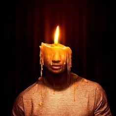 a man with a candle on his head in front of a dark background that looks like it is melting