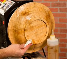 a person is using a brush to clean a wooden plate with an air freshener