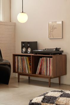 a record player sitting on top of a wooden cabinet next to a black leather chair