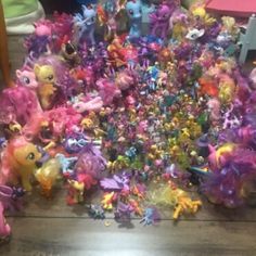 a pile of little pony toys sitting on top of a wooden floor