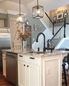 a kitchen with an island, sink and refrigerator in it's center area next to stairs