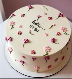 a white cake decorated with pink flowers and the words hello my 80 on it's side