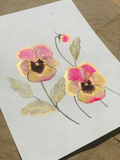 two flowers are painted on a piece of paper with gold leafy stems and pink petals