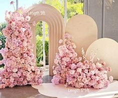 pink flowers are arranged on white pedestals in front of an arch and window sill