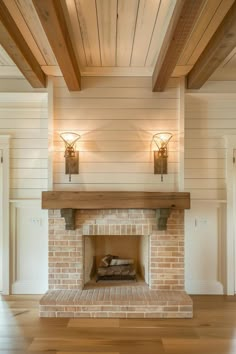 a brick fireplace with two sconces on the wall and wood beams above it