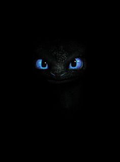 the face of a black cat with glowing blue eyes in the dark, looking straight ahead