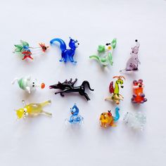 there are many small plastic toy animals on the white table top, all different colors and sizes