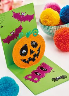 a card with a pumpkin on it next to some pom poms