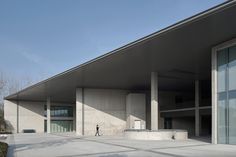 a person walking in front of a building with large windows on the outside and inside