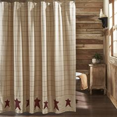 a shower curtain with red stars on it in a rustic cabin style bathroom, next to a window