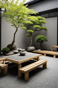 a table and benches in front of a tree with rocks on the ground next to it