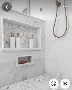 a bathroom with white marble walls and floor, two shower heads are on the wall