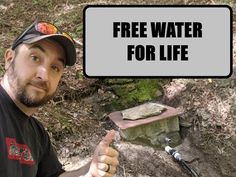 a man with a sign that says free water for life on the side of a rock