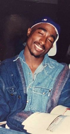 a man sitting down with his eyes closed and holding a book in front of him