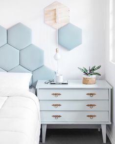 a white bed sitting next to a blue dresser with a plant on top of it