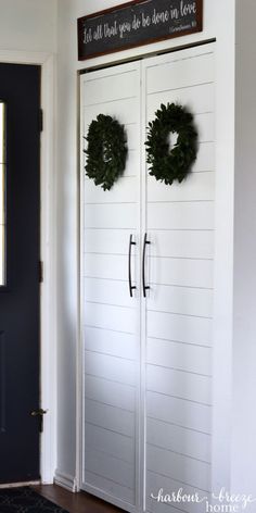 two white double doors with wreaths on them in front of a black and white door