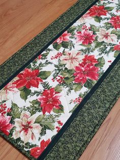 a christmas table runner with poinsettis and holly