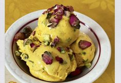 a bowl filled with yellow ice cream on top of a table next to an orange flowered cloth