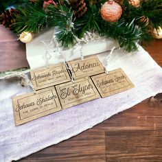 three place cards are sitting on a table next to a christmas tree and pine cones