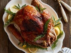 a roasted turkey on a plate with lemons and rosemary garnish