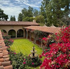 an aerial view of a house with red flowers in the foreground and green lawn