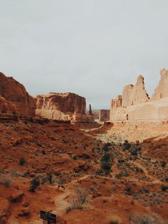 an empty bench sitting in the middle of a desert area with rocks and trees around it