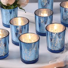 blue glass cups with gold speckles on them and a white rose in the middle