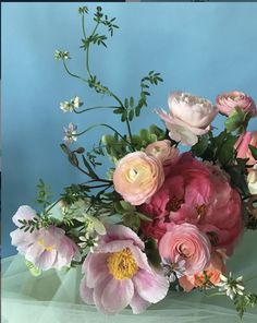 a bunch of flowers that are sitting on a blue table cloth and some green leaves