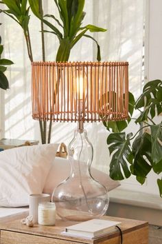 a table with a lamp on top of it next to a plant in a vase