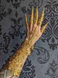 a woman's hand with gold painted nails and bracelets on top of it