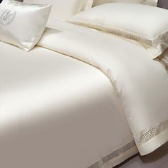 a bed with white sheets and pillows on top of it