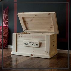 a wooden toy box sitting on top of a hard wood floor next to a wall