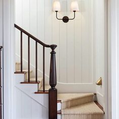 an entry way with stairs and two lamps on the wall