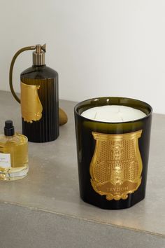 two black and gold candle holders next to each other on a gray surface with a white wall in the background