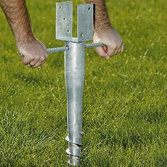 a man is holding onto a metal pole in the grass