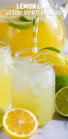 two mason jars filled with lemonade and limes next to some sliced lemons