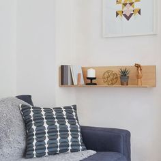 a living room with a blue couch and wooden shelf on the wall next to it