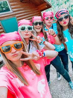 a group of girls in pink shirts and sunglasses making the peace sign with their fingers