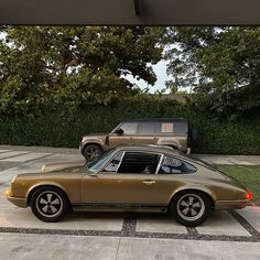 an old porsche parked in a driveway next to two suvs on the other side