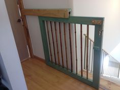 an empty room with wooden floors and green railings on the door, next to a white wall