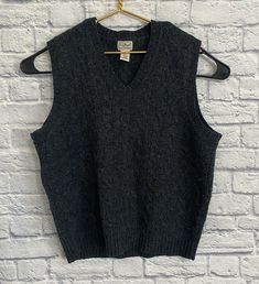 a black sweater vest hanging on a brick wall