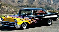 a yellow and black car with flames on it's hood parked in a parking lot