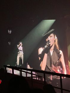 two people on stage with microphones in front of them and one person standing up