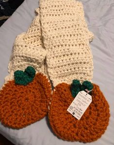 two crocheted pumpkins sitting on top of a bed next to each other