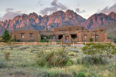 an adobe - style house sits in front of the mountains