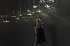 a woman standing in front of a chandelier with lights hanging from the ceiling